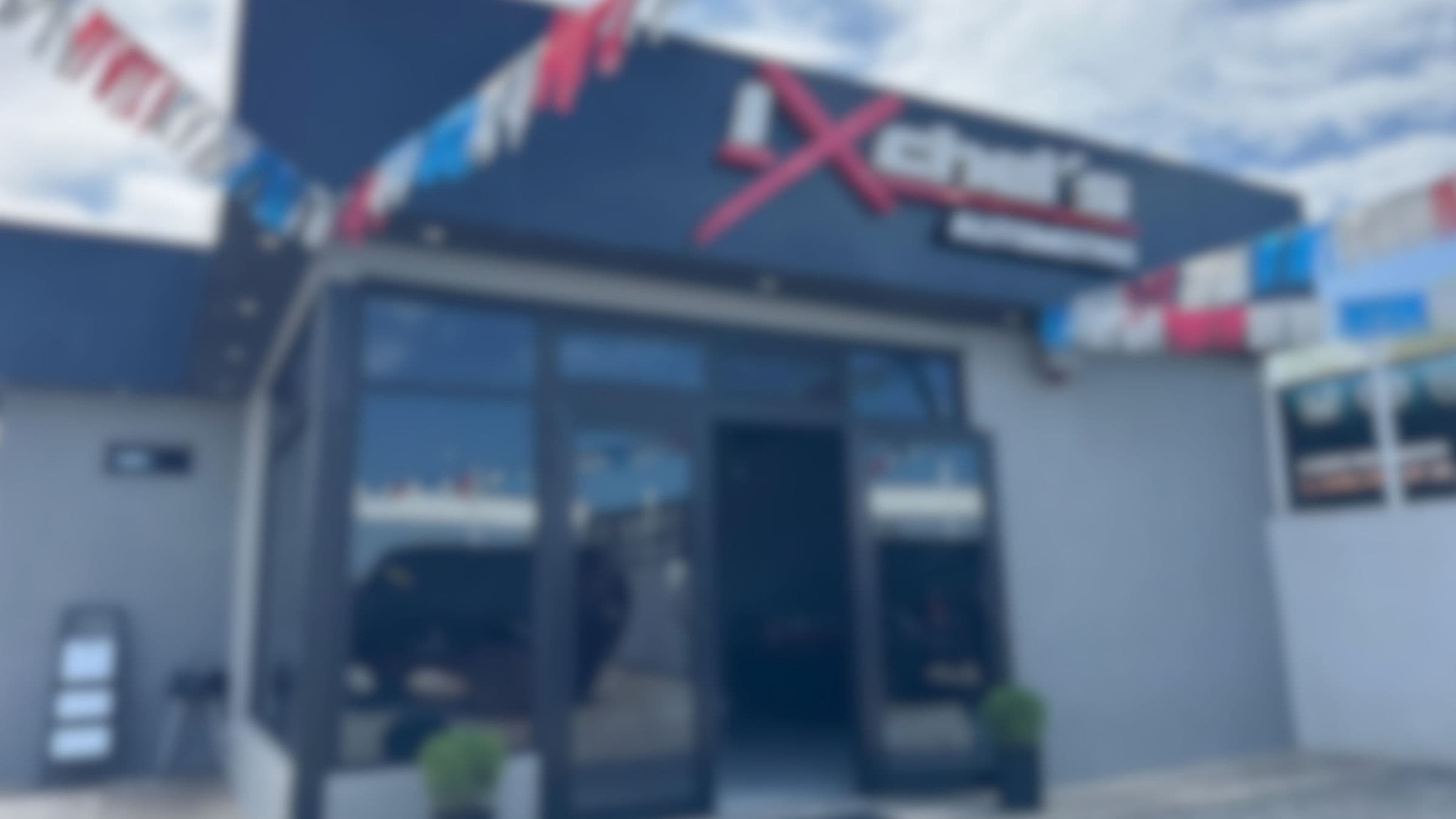 Fachada de Ixchel's Automotriz en Ensenada, con su letrero y banderines de colores