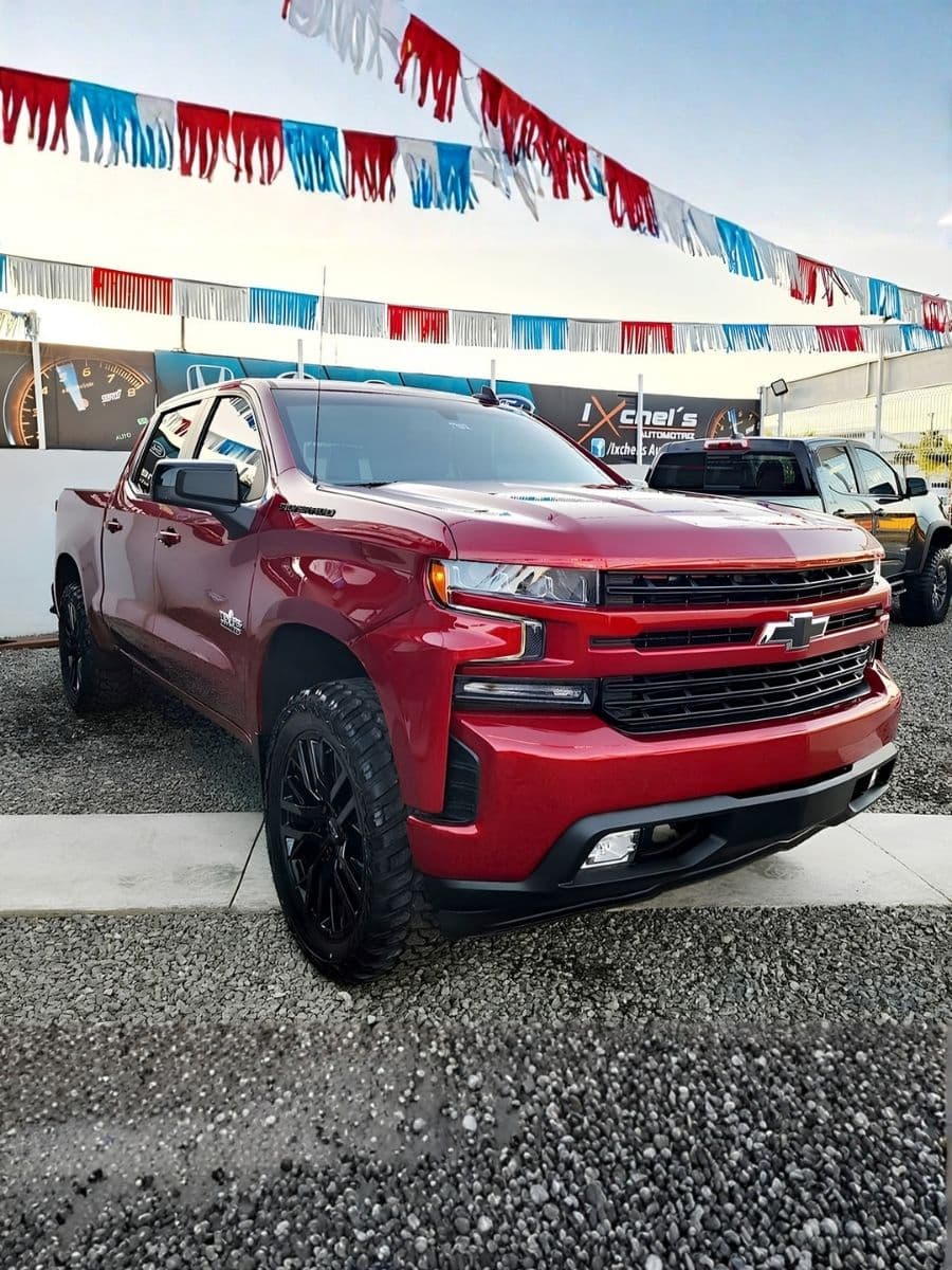 Chevrolet Silverado roja en el lote de Ixchel's Automotriz, bajo banderines de colores